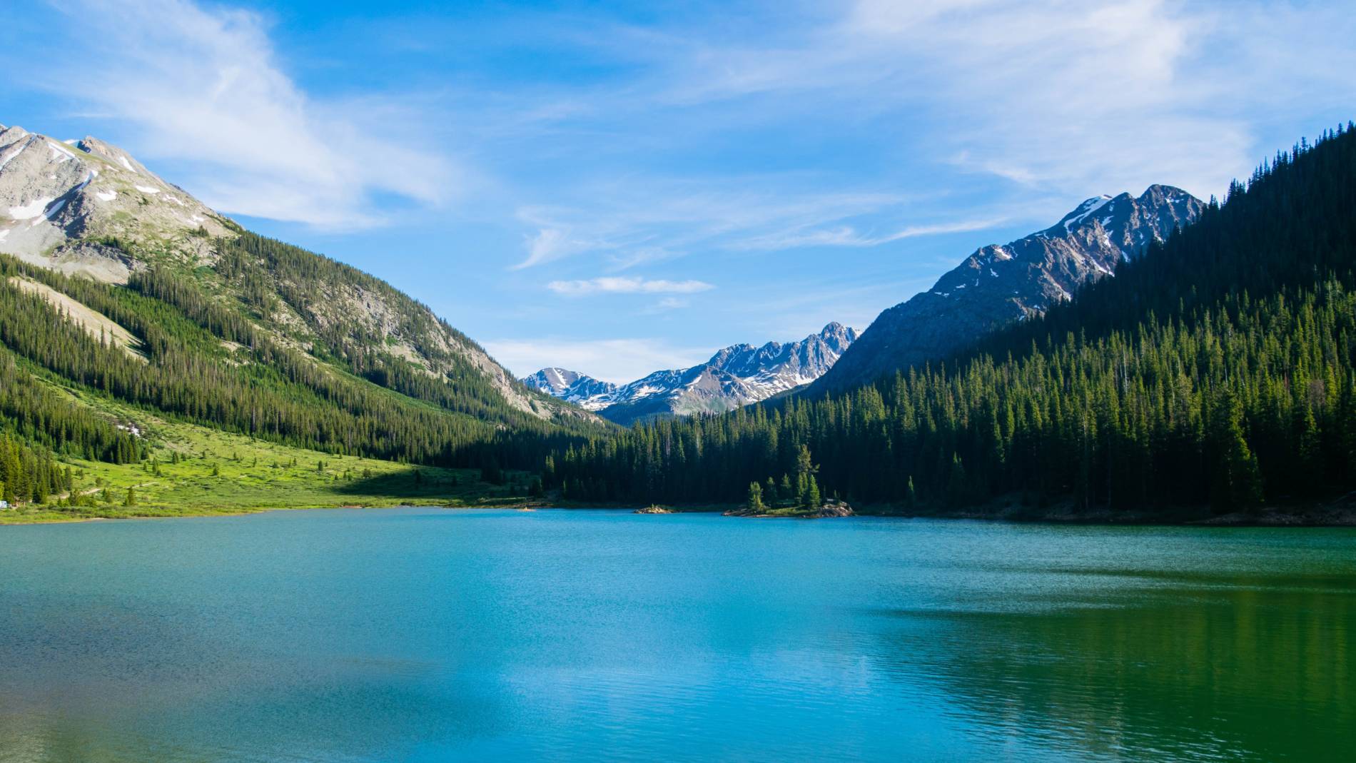 A lake in the mountains with snow on the surrounding peaks.