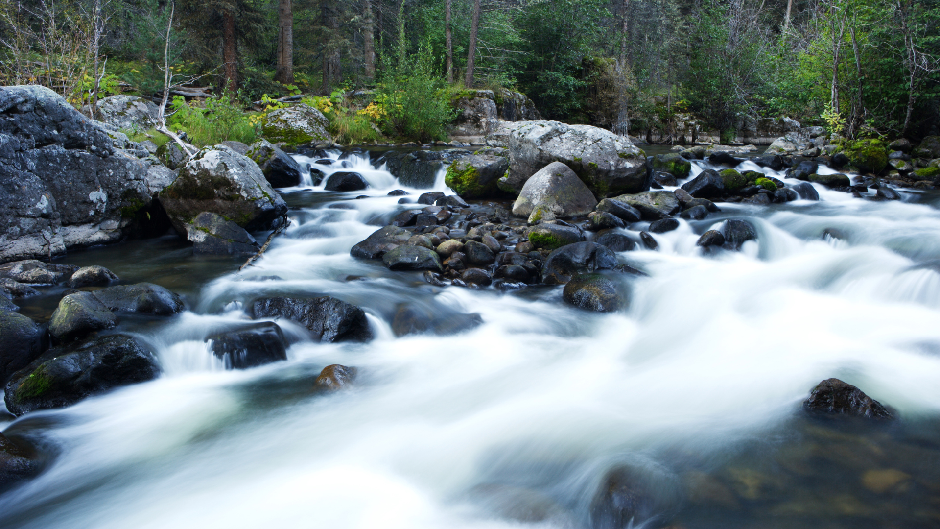 Flowing river around large rocks with soft long exposure of the water