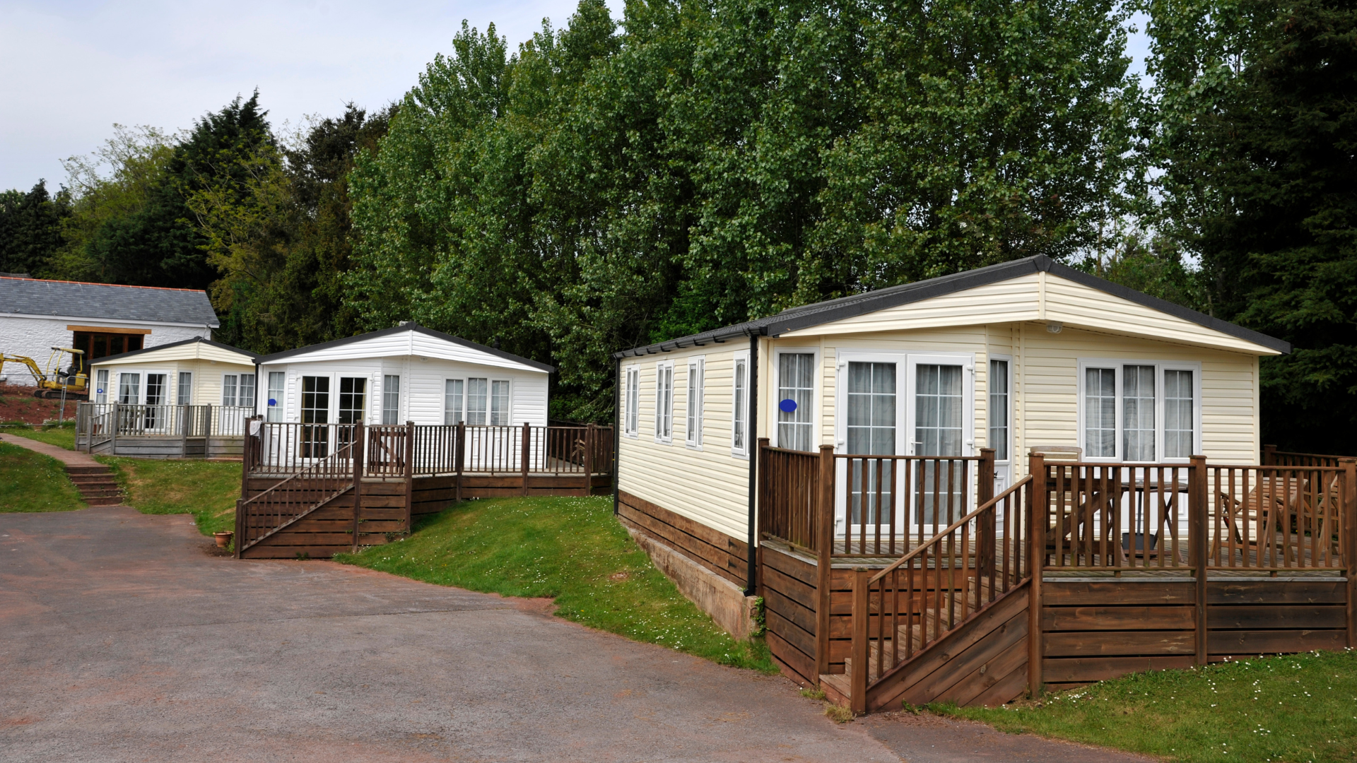 mobile homes line a paved road with green trees in the background