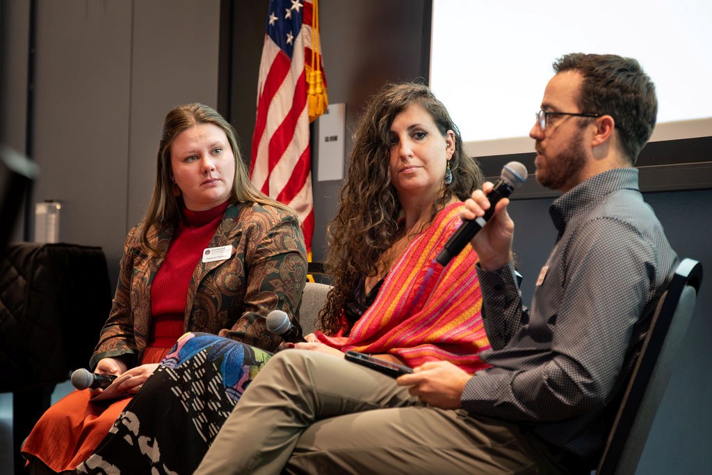 Three panelists speak during the “Serving on Water Boards and Commissions” session at the Water Leadership Summit, with one man speaking into a microphone and two women panelists listening beside him.