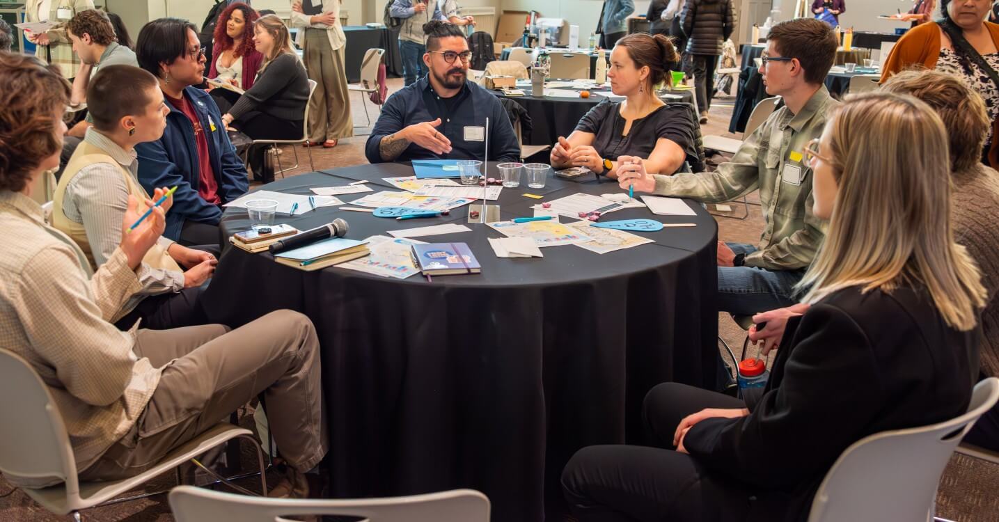 Eight Colorado Water Fellow students and staff in focused discussion at a round table.